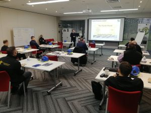 people sat in a classroom listening to someone give a talk.